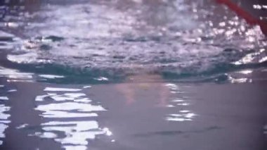 Havuzda yüzen altın şapkalı bir adam.