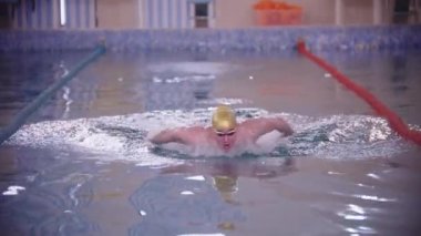 Pistteki havuzda yüzen altın şapkalı bir adam.