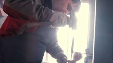 Demirci çekiç ve çarpma makinesiyle metal bir detayı şekillendiriyor.