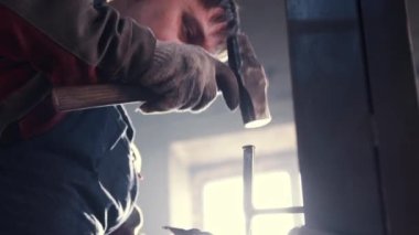 Demirci keskin ataçlarla ve çekiçle hararetli detayları vurur.