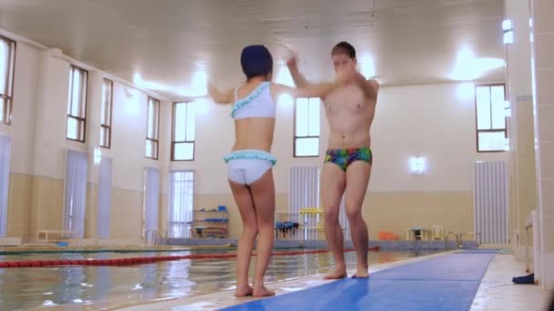 Instructor de natación calentándose con su alumna junto a la piscina — Vídeo de stock