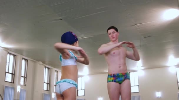 Інструктор з плавання зігріває своє тіло зі своїм маленьким студентом дівчинки — стокове відео