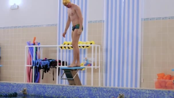 Ein Schwimmer springt von der Tribüne ins Wasser — Stockvideo