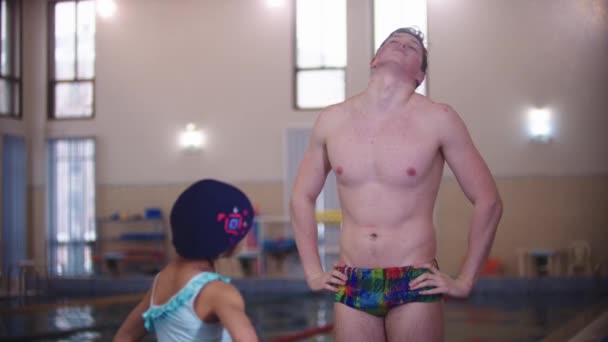 A little girl warming up her neck before swimming with her swimming instructor — Stock Video