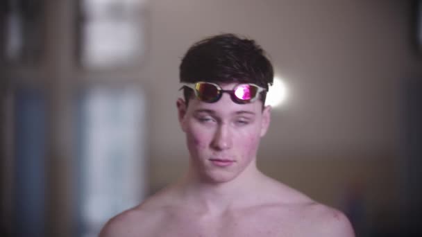 A man swimmer puts on his goggles and looks in the camera — ストック動画