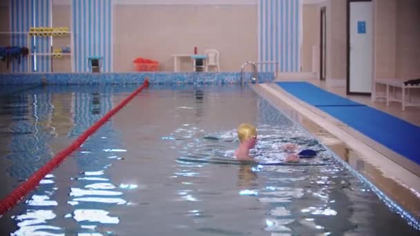 Інструктор з плавання навчає дитину плавати в басейні — стокове відео