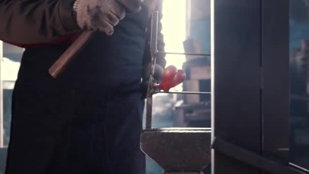 Hombre herrero pone detalle caliente en clips afilados y golpearlo con un martillo — Vídeo de stock