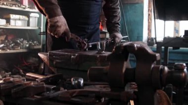 Demirci adam forseps kullanarak metal bir gülün yapraklarını büker.