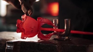 Demirci adam forseps kullanarak metalden gül yapıyor.