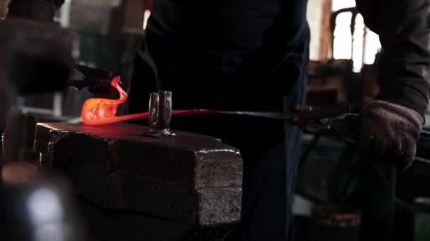 O ferreiro tira aquecido pedaço oblongo de metal e começa a dobrar-se usando fórceps — Vídeo de Stock