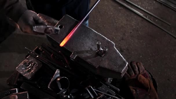 鍛冶屋はハンマーで打つことによって長い赤熱した金属の詳細を曲げる — ストック動画