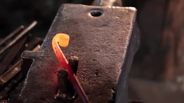 Herrero dobla en una espiral un detalle de metal calentado oblongo golpeando con un martillo — Vídeos de Stock