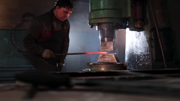 Homem ferreiro diluir um pedaço de metal oblongo sob uma prensa automática — Vídeo de Stock