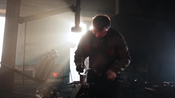 Hombre herrero formando pieza caliente de metal usando un martillo — Vídeos de Stock