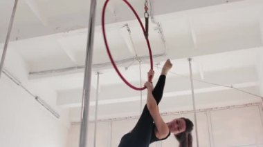 Jimnastik yapan kadın tavanın altındaki yüzüğe asılıyor ve üzerinde dönüyor.