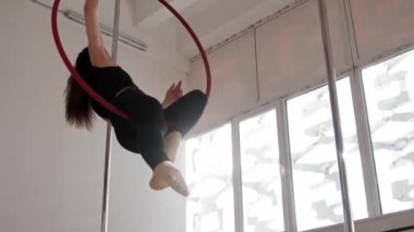 Genç bir kadın beyaz stüdyoda jimnastik ringinde dönüyor.