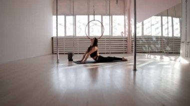 Beyaz stüdyoda yoga minderi üzerinde egzersiz yapan genç bir kadın.