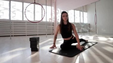 Beyaz stüdyoda yoga minderinin üzerinde uzanan zayıf bir kadın.