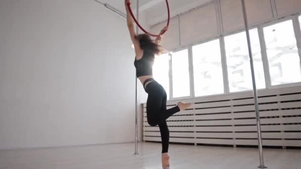 A young gymnastic woman spinning holding by the ring hanging under the ceiling — ストック動画