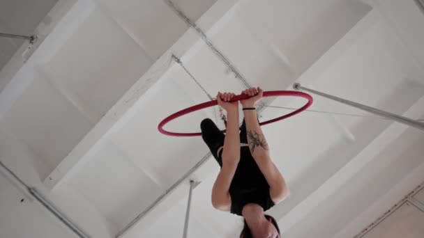 Egy fiatal nő lóg és forog fejjel lefelé akrobatikus gyűrű lóg a plafon alatt — Stock videók