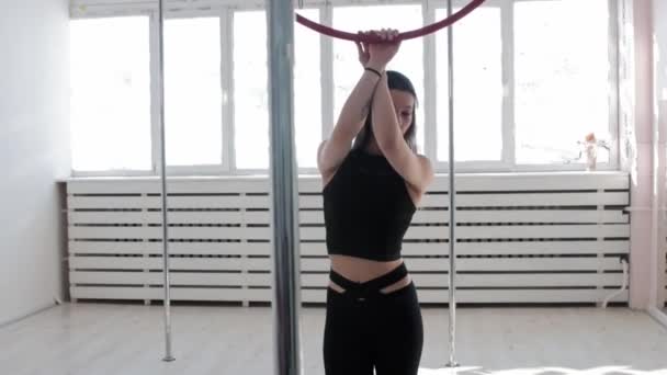 A young woman gymnast holding by an acrobatic ring and looking in the camera — Stock Video