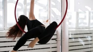 Genç bir kadın jimnastikçi akrobatik ringde oturuyor.