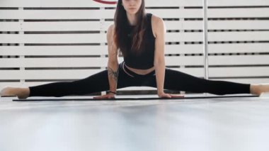 Fitness - genç bir kadın jimnastikçi ikiye ayrılır ve öne eğilir.
