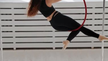 Jimnastik eğitimi. Tavanın altındaki akrobatik ringe tırmanan genç bir kadın.