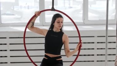 Jimnastik eğitimi. Akrobatik ringde otururken havada sallanan genç bir kadın.