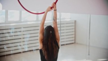 Jimnastik eğitimi. Akrobatik halkayla tutunup tırmanan genç bir kadın.