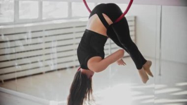 Tavanın altında akrobatik bir yüzükle genç jimnastik yapan bir kadın.