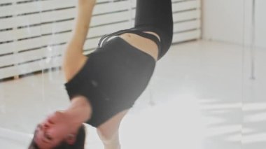 Tavanın altında asılı akrobatik halkada dönen genç bir jimnastik kadını.