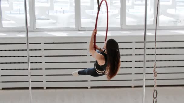 Gymnastic training - young woman climbs onto the acrobatic ring - posing and spinning around
