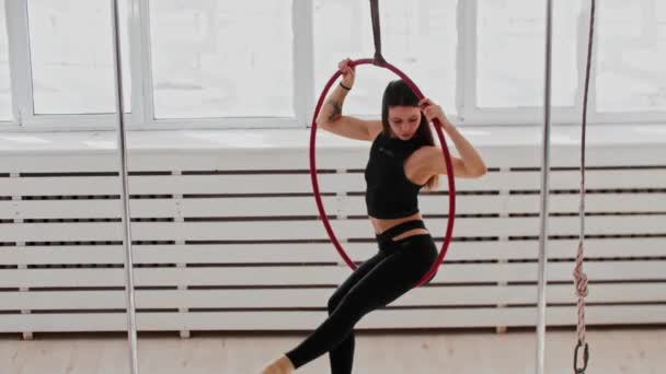 Entrenamiento gimnástico - mujer joven haciendo trucos acrobáticos en el anillo colgando bajo el techo — Vídeos de Stock