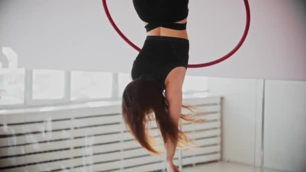 Молода гімнастка тренує акробатичні трюки з кільцем, що звисає догори ногами — стокове відео