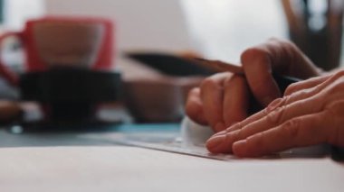 Yaşlı bir kadın sanatçı cetvel kullanarak kağıda resim çiziyor.