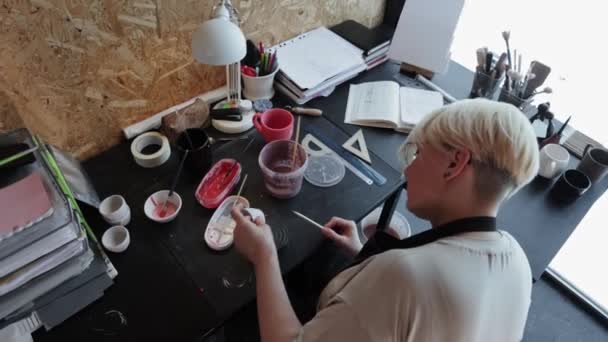 An elderly woman makes recesses on a ceramic mug — Stockvideo