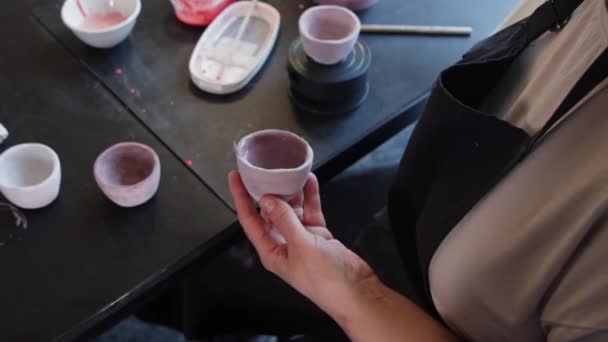 Una anciana pintando taza de cerámica en polvo morado — Vídeo de stock