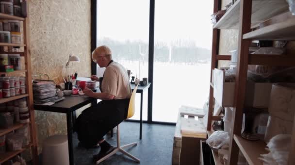 Uma mulher idosa misturando cores para pintar cerâmica — Vídeo de Stock