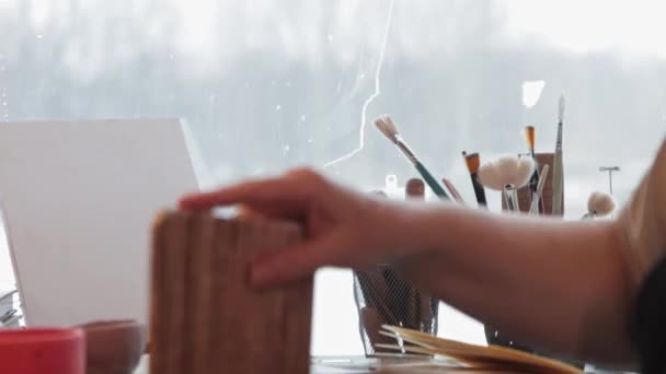 An elderly woman covers a clay plate with a special solution using a big brush — Stock Video