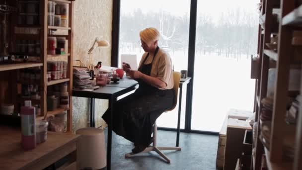 Yaşlı bir kadın ressam kil üzerine resim yapıyor. — Stok video