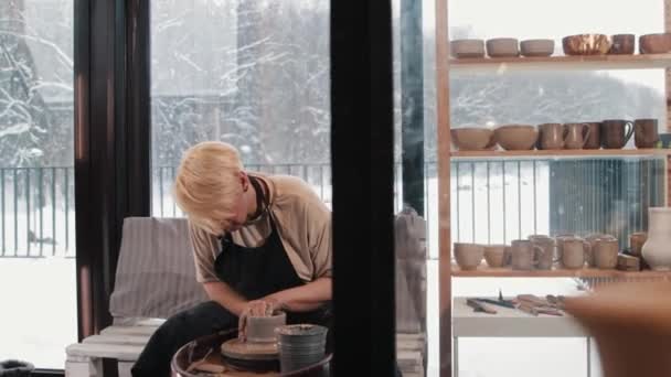 車輪のそばの工房で働く年配の女性陶芸家 — ストック動画