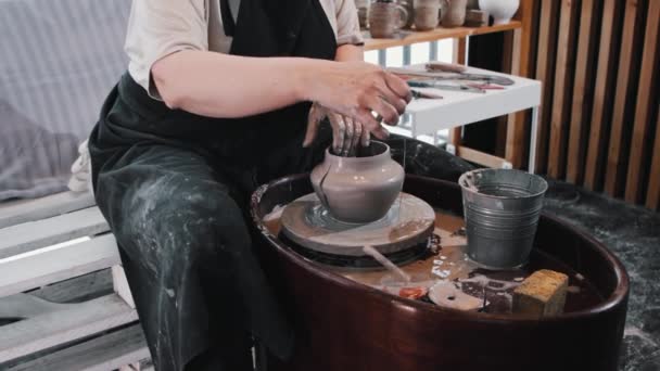 Пожилая женщина гончар режет мокрый глиняный горшок на две половины и переделывает его — стоковое видео