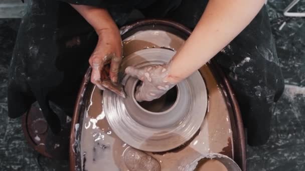 Aardewerk - een vrouw dunner de zijkanten op natte klei pot op het pottenbakkerswiel — Stockvideo
