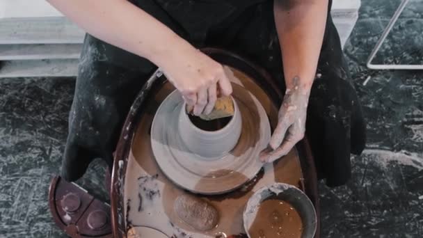 도기 - 손가락 과 스폰지를 사용하여 바퀴에 묻은 진흙 항아리에 옆면을 꿰고 있는 여자 — 비디오