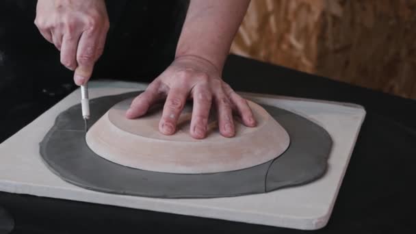 Cerâmica - uma mulher corta uma peça de barro laminado pela amostra de uma placa — Vídeo de Stock