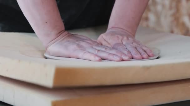 Pottery - an elderly woman pushes through a piece of clay using the sample of plate — Stockvideo