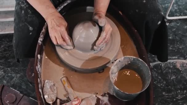 Керамика - пожилая женщина, мочащая глину на гончарном круге — стоковое видео