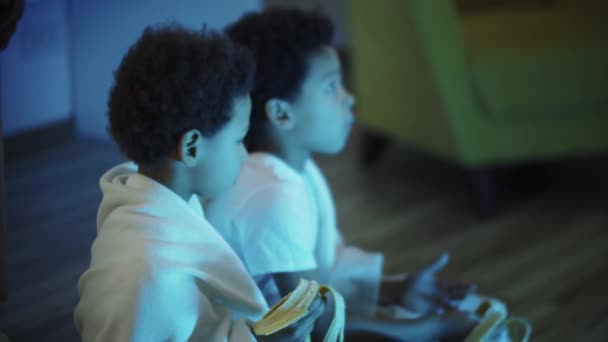 Двоє маленьких чорних хлопчиків сидять на підлозі і їдять банани — стокове відео