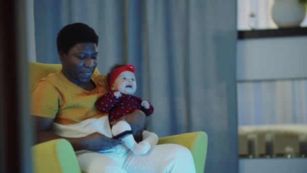 Solo el padre sostiene a su bebé y ve la televisión — Vídeos de Stock